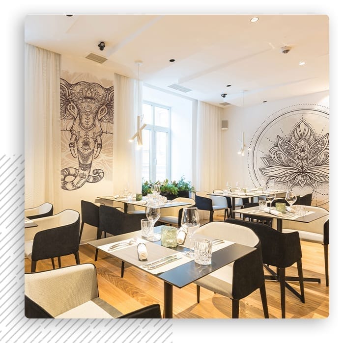 Jasna sala restauracji ze stolikami i ornamentową fototapetą na ścianach